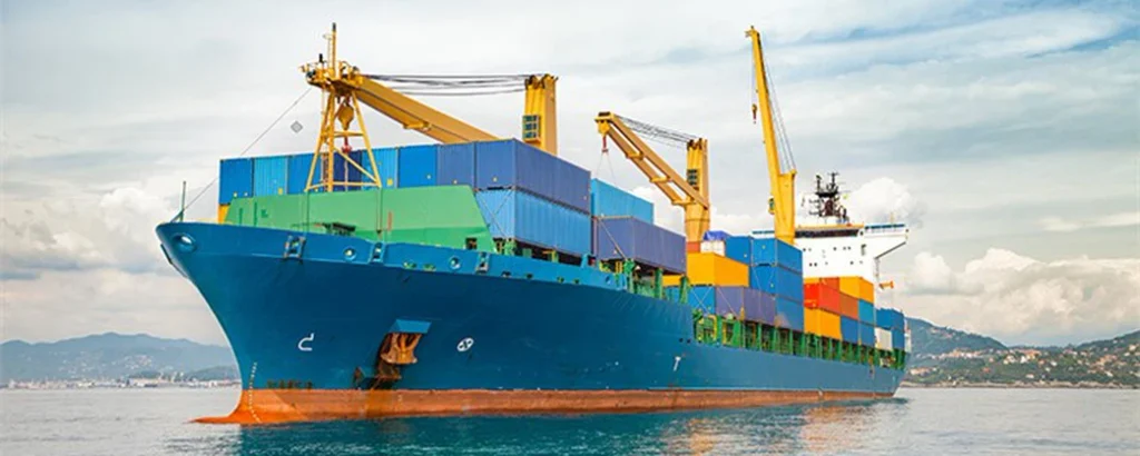 A large blue container ship loaded with colorful shipping containers sailing on the ocean, representing sea freight shipping from China to Saudi Arabia.